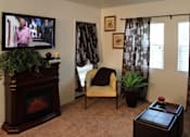 Thumbnail 28 of 126 - A living room with a fireplace, chair, and a television.