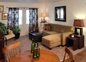 Thumbnail 16 of 126 - A living room with a brown couch, a wooden table, and a chair.
