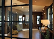 Thumbnail 31 of 126 - A modern living room with a glass door and a brown sofa.