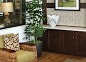 Thumbnail 106 of 126 - A living room with a chair, a plant, a table, and a picture on the wall.