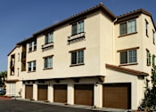 Thumbnail 122 of 126 - A two-story building with a beige facade and brown garage doors.