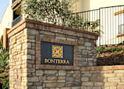 Thumbnail 89 of 126 - A stone wall with a sign that says Bonterra in front of a tan building.