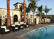 Thumbnail 58 of 126 - A pool area with palm trees and lounge chairs.