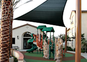 Thumbnail 55 of 126 - A playground with a green slide and a black bench.