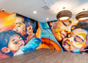 Thumbnail 15 of 16 - A colorful mural of a man and a woman's faces on a wall.