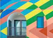 Thumbnail 6 of 16 - A building with a balcony and a doorway.