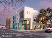 Thumbnail 1 of 16 - A white building with a green trim is on a street corner.