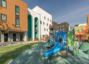 Thumbnail 5 of 16 - A playground with a blue slide and a green hill.