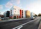 Thumbnail 11 of 16 - A modern building with white and orange accents sits on a street corner.