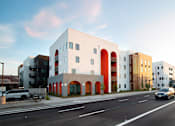 Thumbnail 10 of 16 - A white building with red arches is situated on a street with cars.