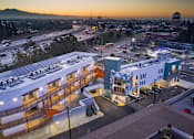 Thumbnail 5 of 11 - A sunset view of a cityscape with a large building in the foreground.