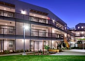 Thumbnail 1 of 11 - A modern building with a green lawn in front.