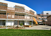 Thumbnail 10 of 11 - A modern building with a white and brown exterior and a green lawn in front.