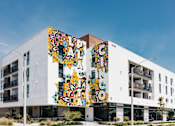 Thumbnail 9 of 17 - A white building with a colorful mural on the side.