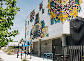 Thumbnail 12 of 17 - A colorful mural on a building with a playground in front.