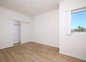 Thumbnail 8 of 17 - A room with white walls and wooden flooring with a window.