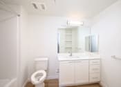 Thumbnail 17 of 17 - A white bathroom with a toilet, sink, and mirror.