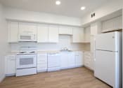 Thumbnail 15 of 17 - A white kitchen with a refrigerator on the right.