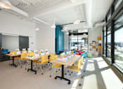 Thumbnail 6 of 17 - A conference room with yellow chairs and white tables.