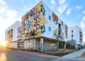 Thumbnail 3 of 17 - A white building with a colorful mural on the side.