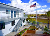 Thumbnail 2 of 2 - A white building with a flag on top and a staircase leading to the second floor.