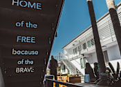 Thumbnail 1 of 2 - A sign with the words "Home of the Free because of the Brave" is displayed on a wall.