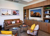 Thumbnail 18 of 102 - A living room with a brown couch, a coffee table, and a large painting on the wall.