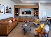 Thumbnail 15 of 102 - A living room with a brown couch, a coffee table, and a large painting on the wall.