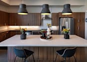Thumbnail 20 of 102 - A modern kitchen with a white countertop and dark chairs.