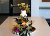 Thumbnail 31 of 102 - A black lamp with a yellow glow hangs over a table with a floral arrangement.
