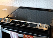 Thumbnail 30 of 102 - A black oven with a digital display and knobs on top.