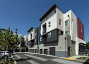 Thumbnail 34 of 102 - A modern multi-story building with a parking lot in front.