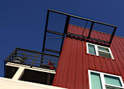 Thumbnail 38 of 102 - A red building with a balcony and a black railing.