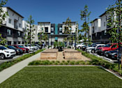 Thumbnail 44 of 102 - A parking lot with cars and apartment buildings in the background.