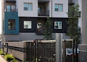 Thumbnail 61 of 102 - A black fence runs along a sidewalk in front of a building.
