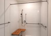 Thumbnail 81 of 102 - A white tiled shower with a bench and a metal drain.