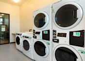 Thumbnail 92 of 102 - A row of white washing machines are lined up in a room.
