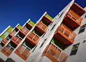Thumbnail 85 of 94 - A tall building with balconies in orange and green.