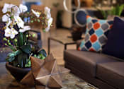 Thumbnail 77 of 94 - A living room with a glass table and a brown couch.