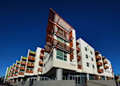 Thumbnail 74 of 94 - A modern building with a white and brown facade and a clear blue sky in the background.