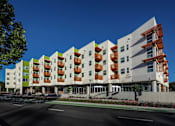 Thumbnail 73 of 94 - A modern building with a green and white exterior and a red balcony railing.