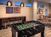 Thumbnail 59 of 94 - A foosball table is in the middle of a room with chairs and artwork on the wall.