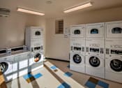 Thumbnail 48 of 94 - A row of white front load washing machines in a laundromat.