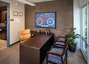 Thumbnail 50 of 94 - A room with a brown desk and a bicycle picture on the wall.