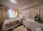 Thumbnail 44 of 94 - A bedroom with a bed and a dresser with a mirror above it.