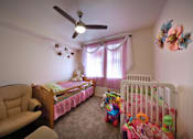 Thumbnail 41 of 94 - A room with a ceiling fan and two beds with toys on the floor.