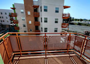 Thumbnail 37 of 94 - A balcony with a brown floor and a railing overlooking a river.