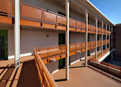 Thumbnail 31 of 94 - A long corridor with orange railings and white pillars.