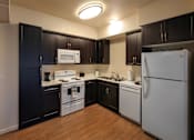 Thumbnail 32 of 94 - A kitchen with a white refrigerator, black cabinets, and a white stove top oven.