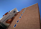 Thumbnail 7 of 94 - A tall building with a brown facade and white balconies.